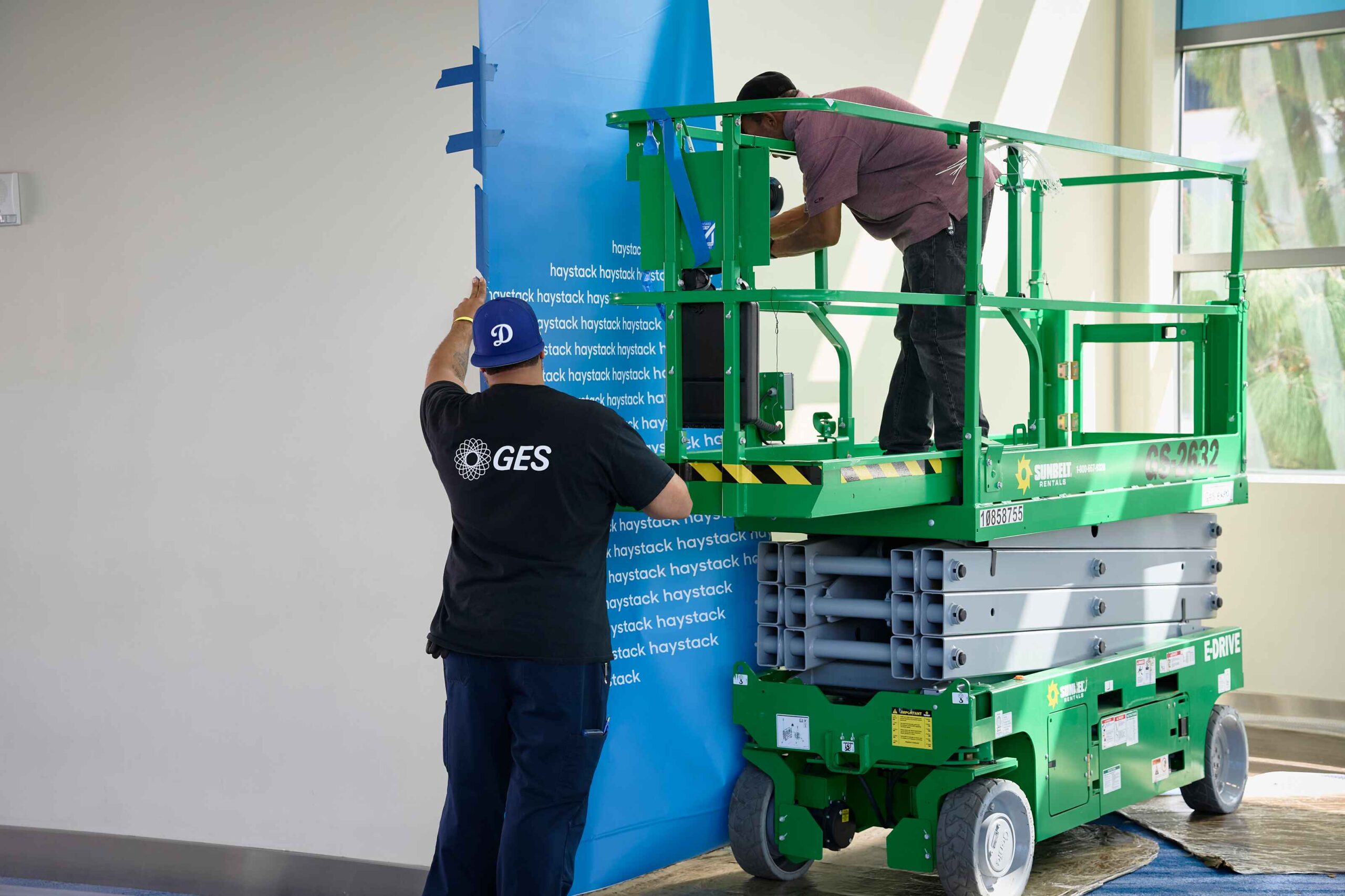Het GES-team werkt ter plaatse op een hoogwerker aan de beursdecoratie.